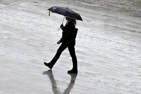Una persona passeggia con un ombrello a Milano in una foto di archivio