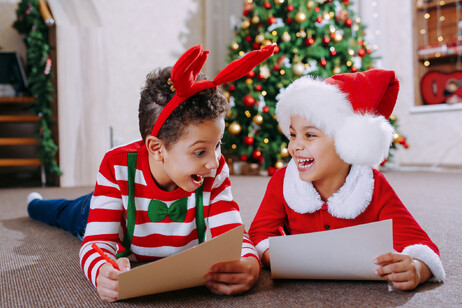 Due bambini sorridono scrivendo la letterina a Babbo Natale foto iStock.