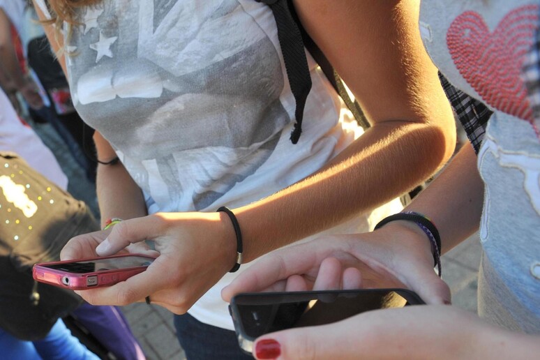 Una foto d 'archivio di adolescenti che consultano i loro smartphone - RIPRODUZIONE RISERVATA