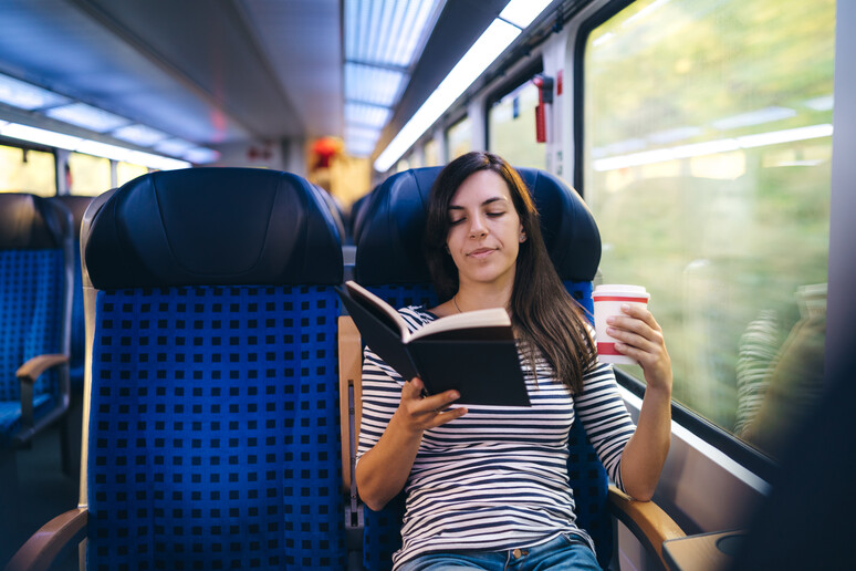 Una donna legge un libro in treno foto iStock. - RIPRODUZIONE RISERVATA